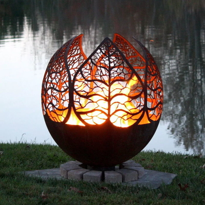 灰皿が付いている鋼鉄地球球の火ピットを風化させる秋の日没の葉